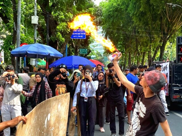 UNJUK GIGI | Seorang peserta aksi menunjukkan kebolehannya dengan menyemprot api menggunakan kaleng aerosol. Hal ini dilakukannya saat sesi aksi teatrikal, Kamis (01/05/2025). | Derista Putri