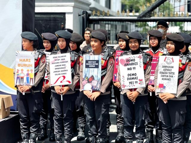 SERUPA | Setibanya di Gedung DPRD Sumut, polisi wanita tampak di barisan depan memegang poster. Terlihat serupa dengan poster yang dibawa oleh massa aksi, namun tentu nilainya tak sama, Kamis (01/05/2025). | Jeremia Rafael Simamora