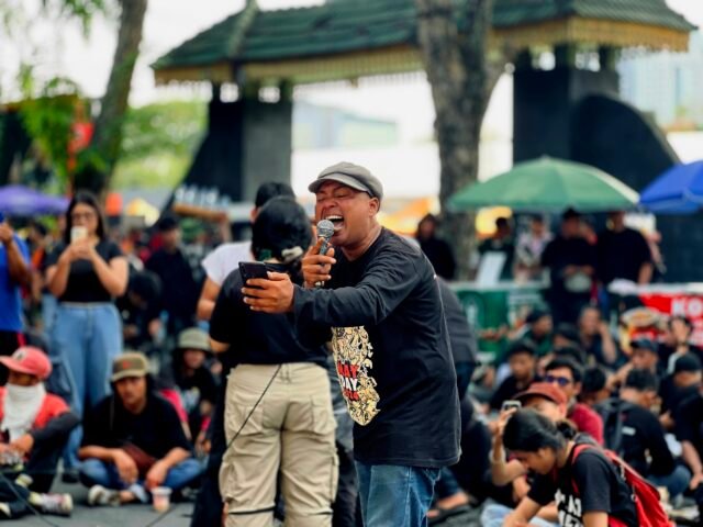 EKSPRESI DIRI | Peserta aksi diberi ruang bebas untuk mengekspresikan diri. Kali ini, seorang pria membaca puisi "Derita Sudah Naik Seleher" karya Widji Thukul di hadapan aparat dan massa aksi, Kamis (01/05/2025). | Jeremia Rafael Simamora