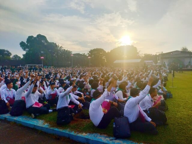 SERENTAK | Para mahasiswa mengangkat gelas cendera mata bersamaan dalam PKKMB USU 2025, Rabu (13/8/2025). | Tio Hasianna Vincentia Hutahaean