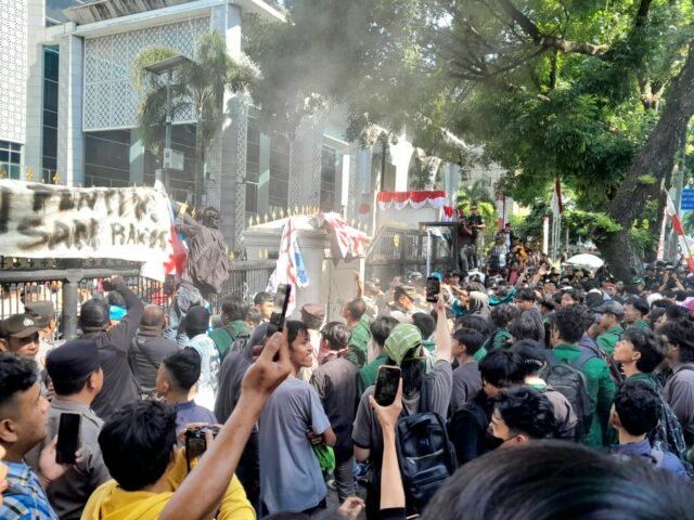 Massa aksi berkerumun dan terlihat salah satu massa menaiki gerbang depan gedung DPRD Sumut, Selasa (26/8/2025). | Dormaulina Sitanggang