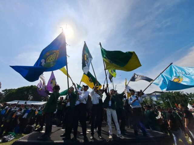 KIBAR | Bendera dari berbagai fakultas dikibarkan tinggi di podium oleh mahasiswa pada PKKMB USU 2025, Rabu (13/8/2025). | Imelda Sari Manalu