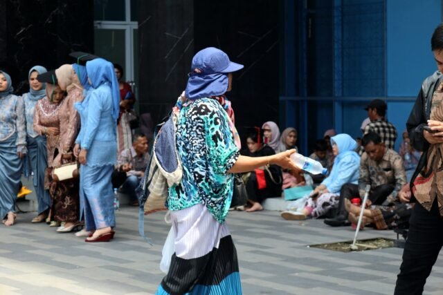 MENJAJAKAN | Tak hanya keluarga, para pedagang juga tak melewatkan momen wisuda. Terlihat seorang pedagang air minum menawarkan dagagannya kepada para tamu wisuda, Jumat (29/8/2025). | Dinar Fazira Fitri