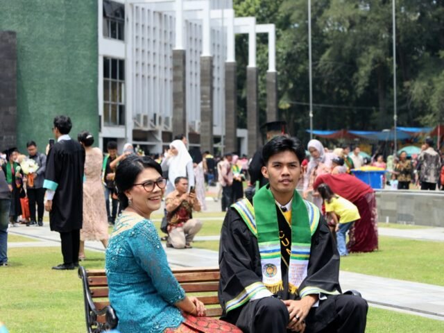 BAHAGIA | Wisudawan duduk berpose bersama ibunya. Keduanya tersenyum bangga merayakan momen wisuda penuh kebahagiaan, Jumat (29/8/2025). | Imelda Sari Manalu