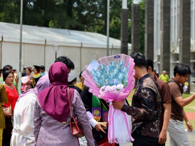 HADIAH | Keluarga menyambut wisudawan dengan sebongkah buket bunga. Hadiah ini menyertai ucapan selamat dan doa, Jumat (29/8/2025). | Imelda Sari Manalu