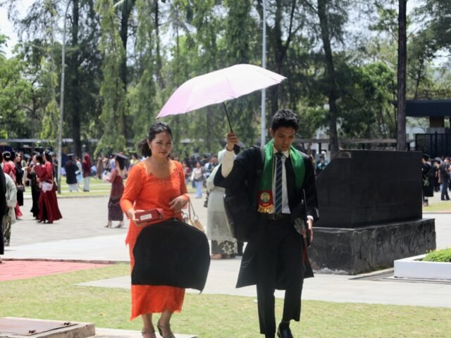BERSAMA | Seorang wisudawan berpayung bersama sang ibu. Sama halnya seperti menuju hari kelulusan ini, ada ibu yang selalu berjalan di sisi, Jumat (29/8/2025). | Imelda Sari Manalu