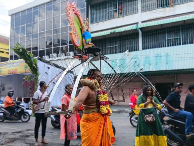 VEL KAVADI | Seorang umat membawa rangka vel kavadi di jalan raya dalam iring-iringan prosesi Thaipusam, Minggu (1/2/2026). | Imelda Sari Manalu
