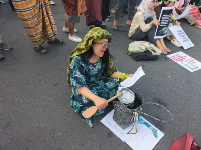 SERUAN | Seorang massa menyuarakan tuntutan sambil memukul panci pada peringatan Hari Perempuan Internasional, Sabtu (7/3/2026). | Cyntia Lorena Br Tarigan