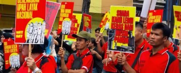 POSTER | Massa aksi tampak membawa berbagai poster bernada tuntutan dengan desain seragam berwarna merah dan kuning. Poster-poster tersebut menjadi simbol perlawanan sekaligus media penyampai aspirasi buruh di tengah aksi, Jumat (1/5/2026). | Iyusarah Pakpahan