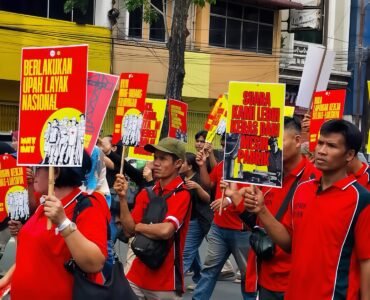 POSTER | Massa aksi tampak membawa berbagai poster bernada tuntutan dengan desain seragam berwarna merah dan kuning. Poster-poster tersebut menjadi simbol perlawanan sekaligus media penyampai aspirasi buruh di tengah aksi, Jumat (1/5/2026). | Iyusarah Pakpahan