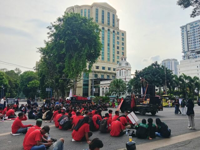 TITIK AKSI | Massa aksi berkumpul dan duduk di lokasi unjuk rasa. Mereka menyimak orasi sebagai bagian dari rangkaian aksi, Jumat (1/5/2026). | Deasy Glorya Situmorang