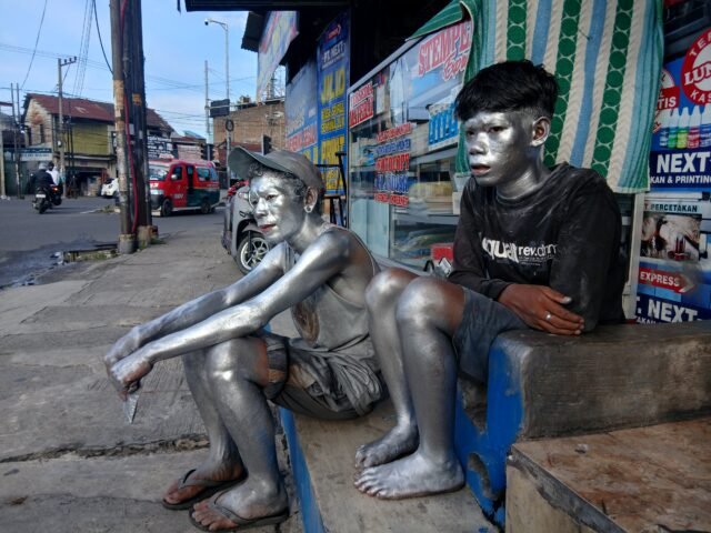 Dua manusia silver tengah duduk di pinggiran toko di jalan Dr Mansyur, Simpang pintu 1 USU, Rabu (17/6/2026)