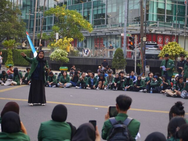 SORAK PUISI | Mahasiswi membacakan puisi di tengah lingkaran massa aksi, menyuarakan keresahan dalam untaian kata, Senin (15/6/2026). | Cyntia Lorena Br Tarigan