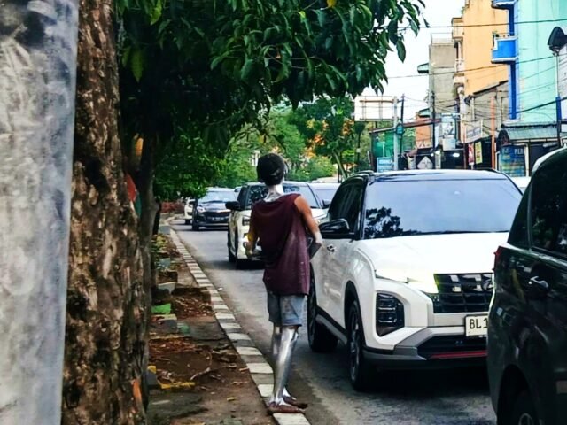 Di siang hari, seorang manusia silver berdiri di trotoar jalan Iskandar Muda, Rabu (13/5/2026). Hasrina Arum Maulida