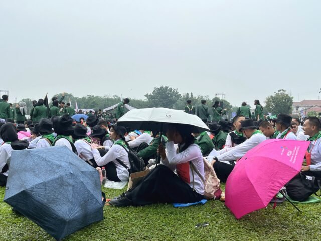 LINDUNG | Tampak seorang mahasiswa menggunakan payung di tengah kerumunan, Rabu (12/8/2026). | Fristania Nadeak